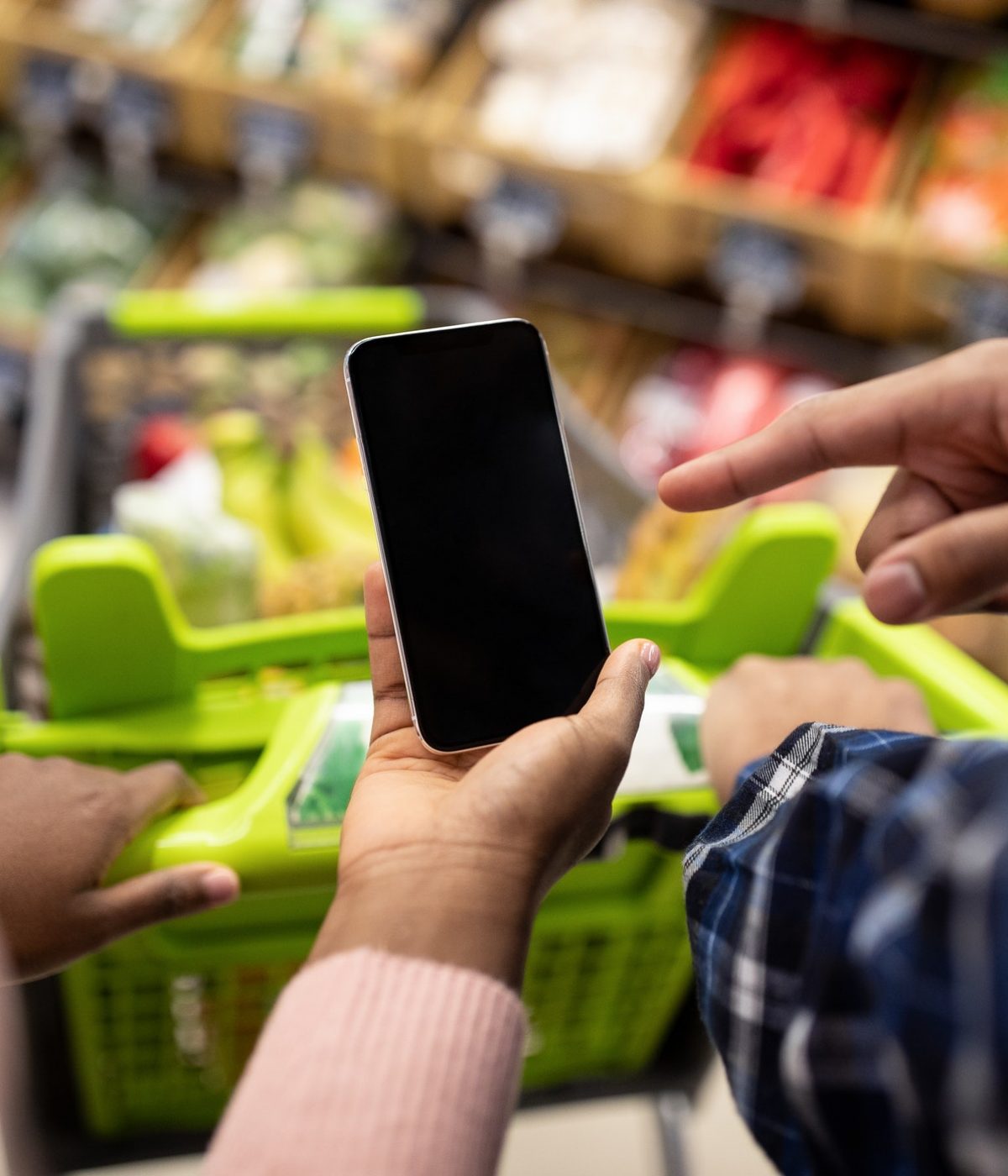 Unrecognizable black couple holding smartphone with empty screen at supermarket, mockup for your